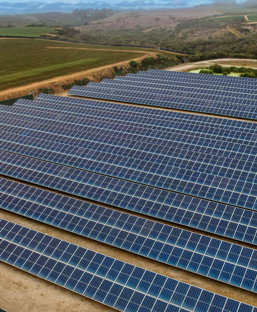 Aerial view of solar panels beside a farm field